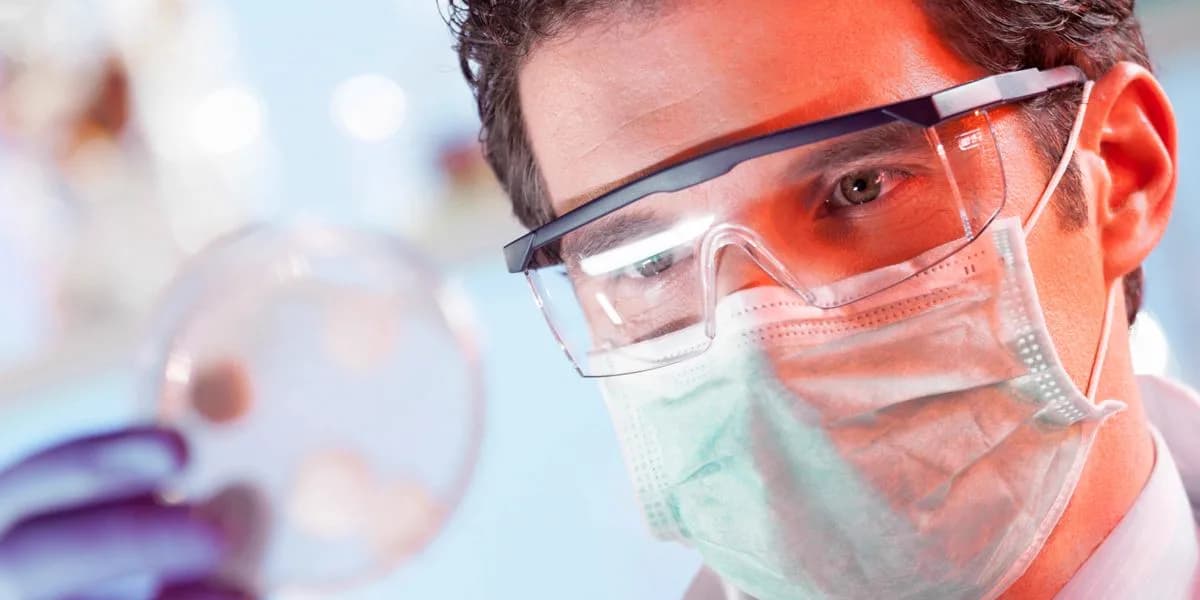 A researcher studies cultures in a petri dish — the science behind integrated aquaculture.