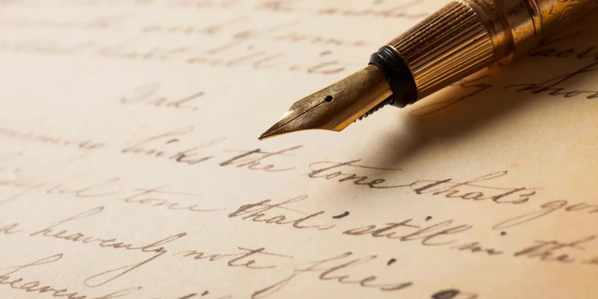 A gold fountain pen resting on a page of flowing handwritten script.